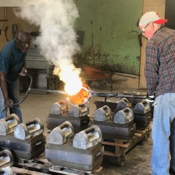 Guys pouring the molten brass into the sand molds